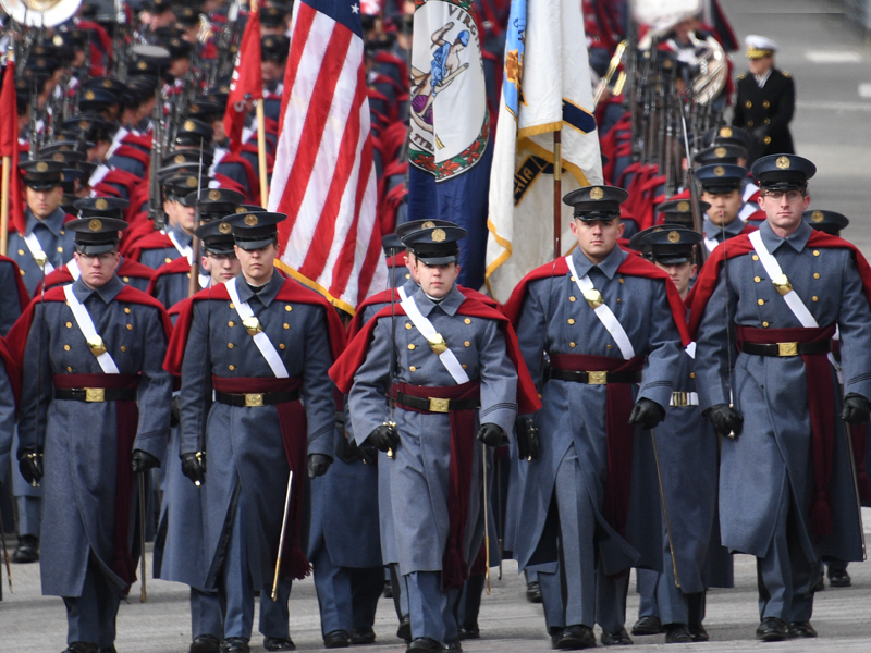 VMI cadet leaders marching in parade in front of flags