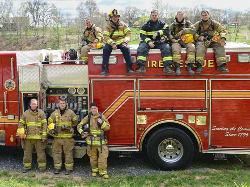 Members of the VMI Fire Fighting Club stand in front of and sit on Lexington City fire truck