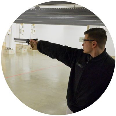 Pistol Club cadet aiming pistol at indoor range photo circle