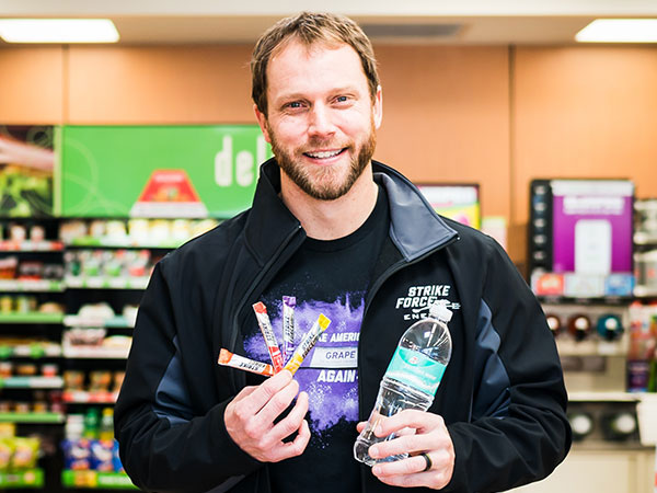 A man holding three packets and a bottle of water