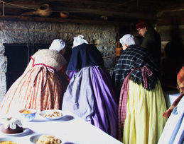 Women wearing traditional clothing from 1860s in a farm kitchen
