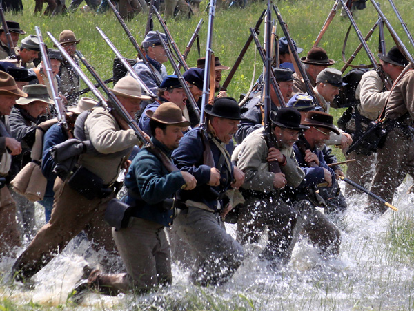 Reenactors charge across field through water