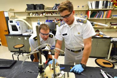 Maj. Dan Harrison ’05 and Jake Hyde ’17 set up a specially designed, air-free, electrochemical cell containing one of Hyde’s iron compounds. – VMI Photo by Kelly Nye.