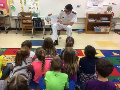 A cadet reads to elementary school students.