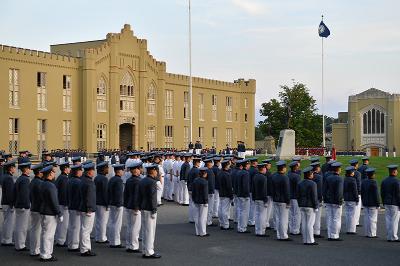 Cadets stand in front of barracks at the end of the day as the evening gun is fired.